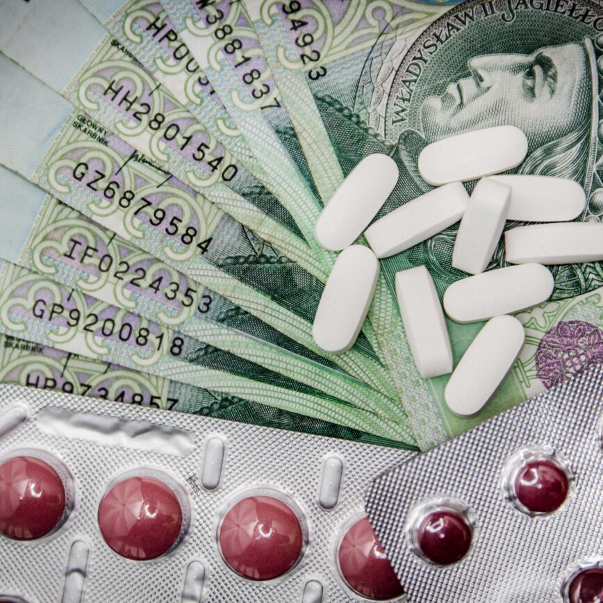 Polish 100 złoty notes with pills and blister packs, illustrating medical costs.