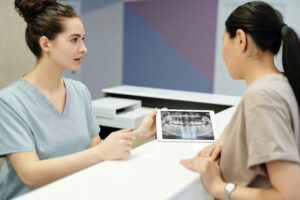 A dentist explains X-ray results to a patient using a tablet in a modern dental clinic.