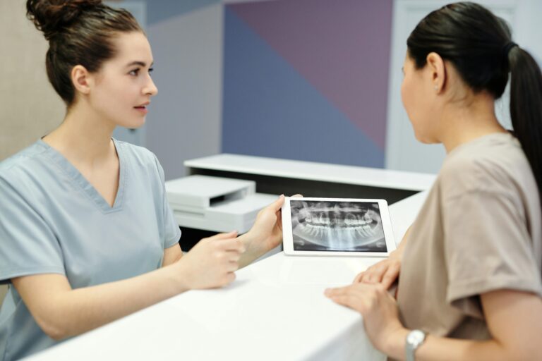 A dentist explains X-ray results to a patient using a tablet in a modern dental clinic.