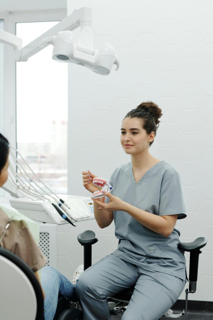 pexels-photo-4269363-4269363 Dental professional demonstrating oral care to a patient using a model in a modern clinic.