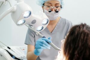 Dentist using tools and lights during a dental examination procedure in a modern clinic.