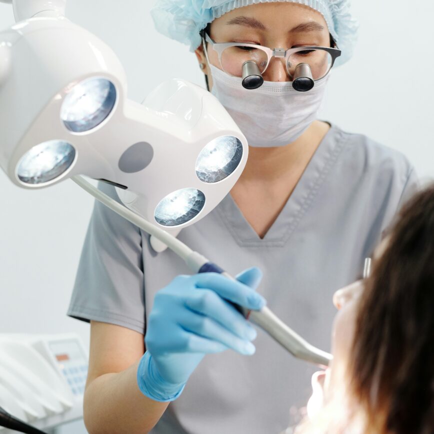 Dentist using tools and lights during a dental examination procedure in a modern clinic.