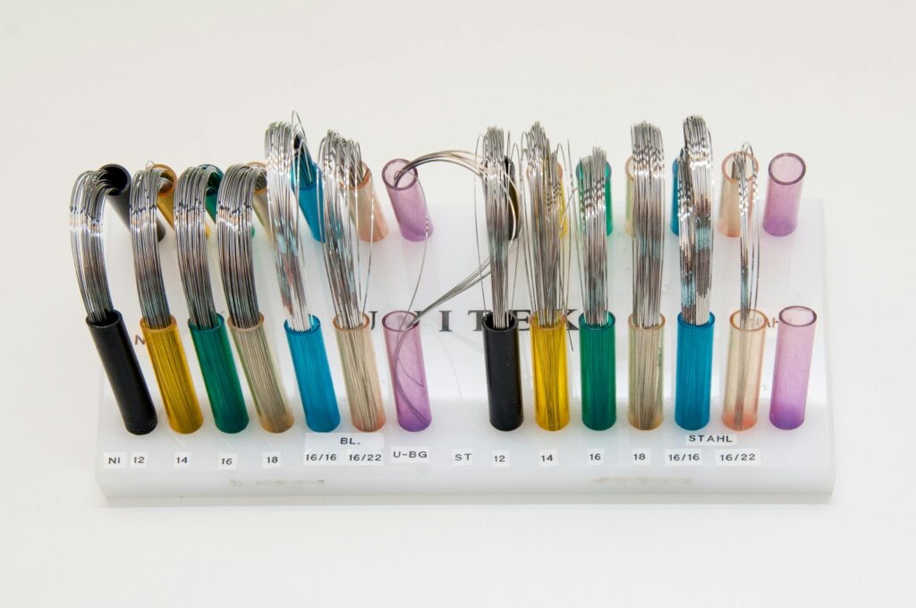 Display of colorful orthodontic wires arranged neatly on a stand.