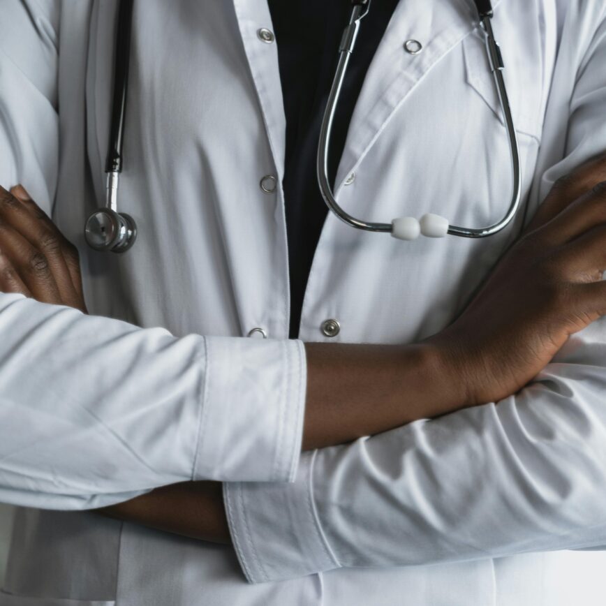 Close-up of a confident doctor in a lab coat standing with crossed arms and stethoscope.