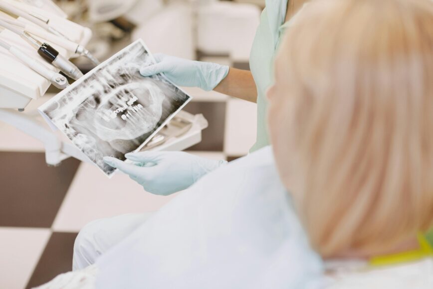 Dental professional reviewing X-ray with patient in a clinic setting. Focus on healthcare and dentistry.