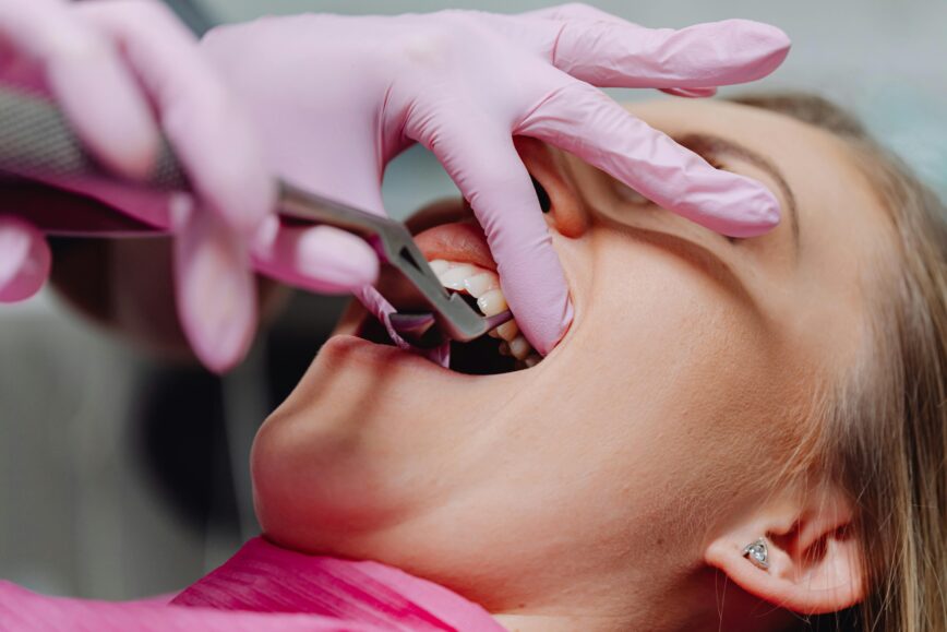 A patient receiving dental care, showcasing pink gloves and dental tools in a clinic setting.