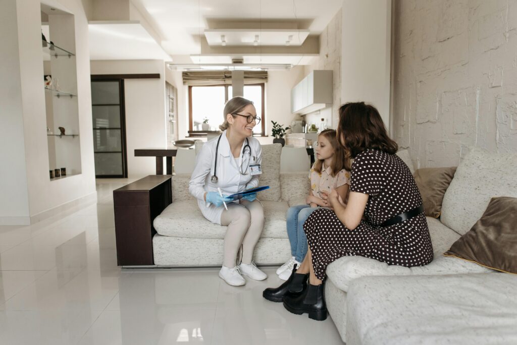 pexels-photo-7653119-7653119 A mother and daughter receive a consultation from a female doctor at home.