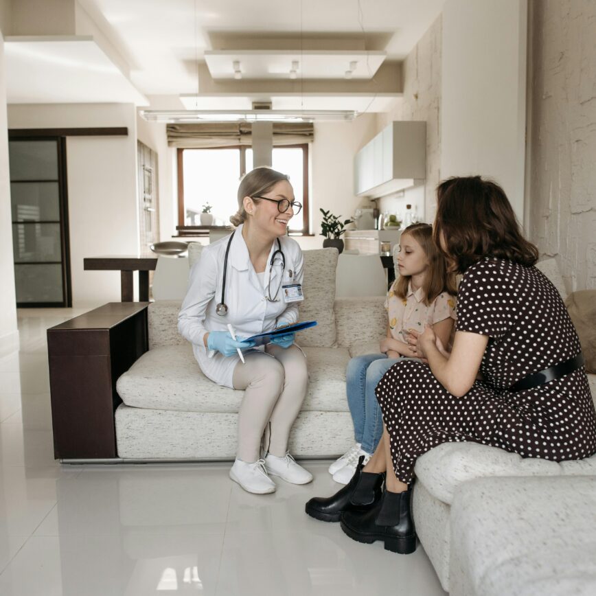 A mother and daughter receive a consultation from a female doctor at home.