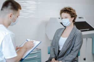 Doctor and patient wearing masks during a medical consultation in a modern healthcare setting.
