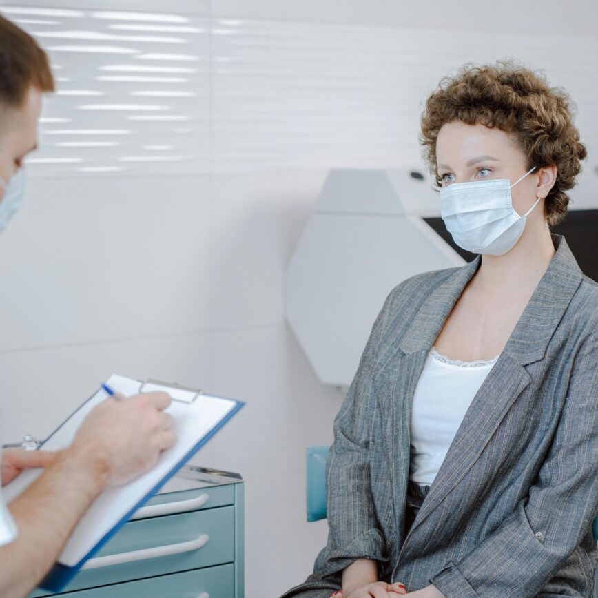 Doctor and patient wearing masks during a medical consultation in a modern healthcare setting.