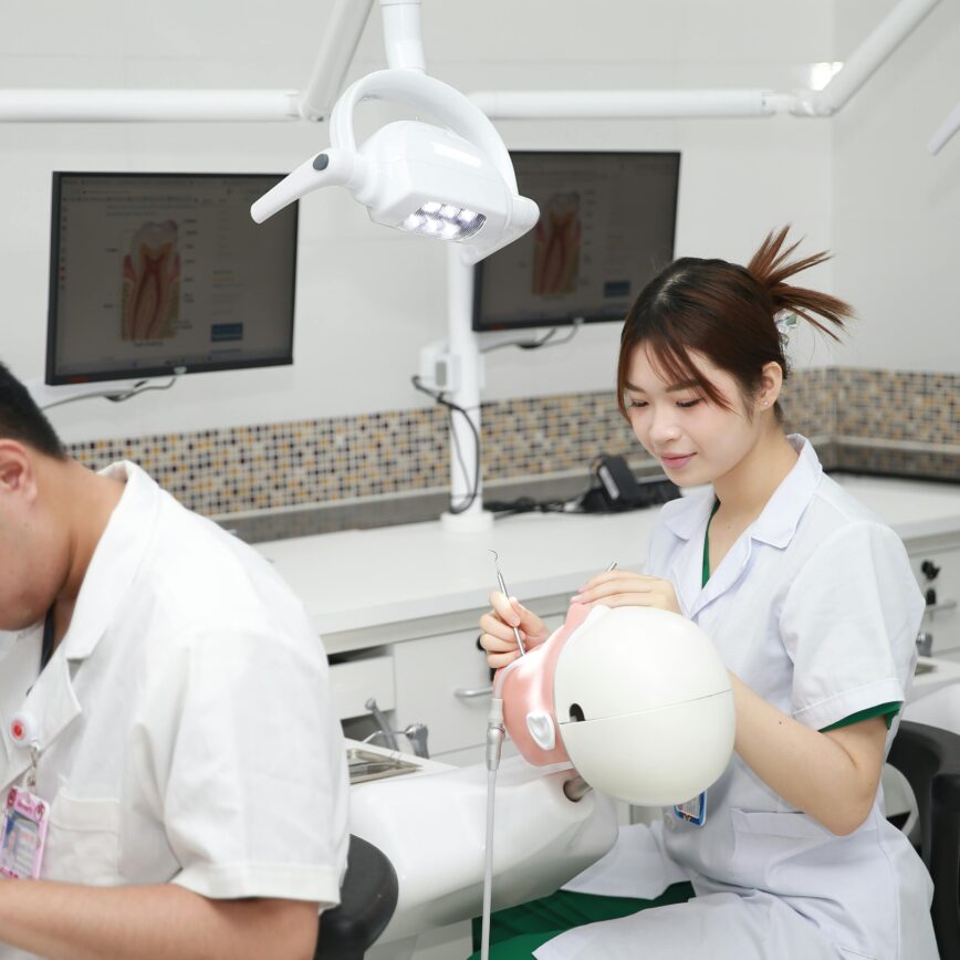Dental students practicing procedures on training models in a classroom setting.
