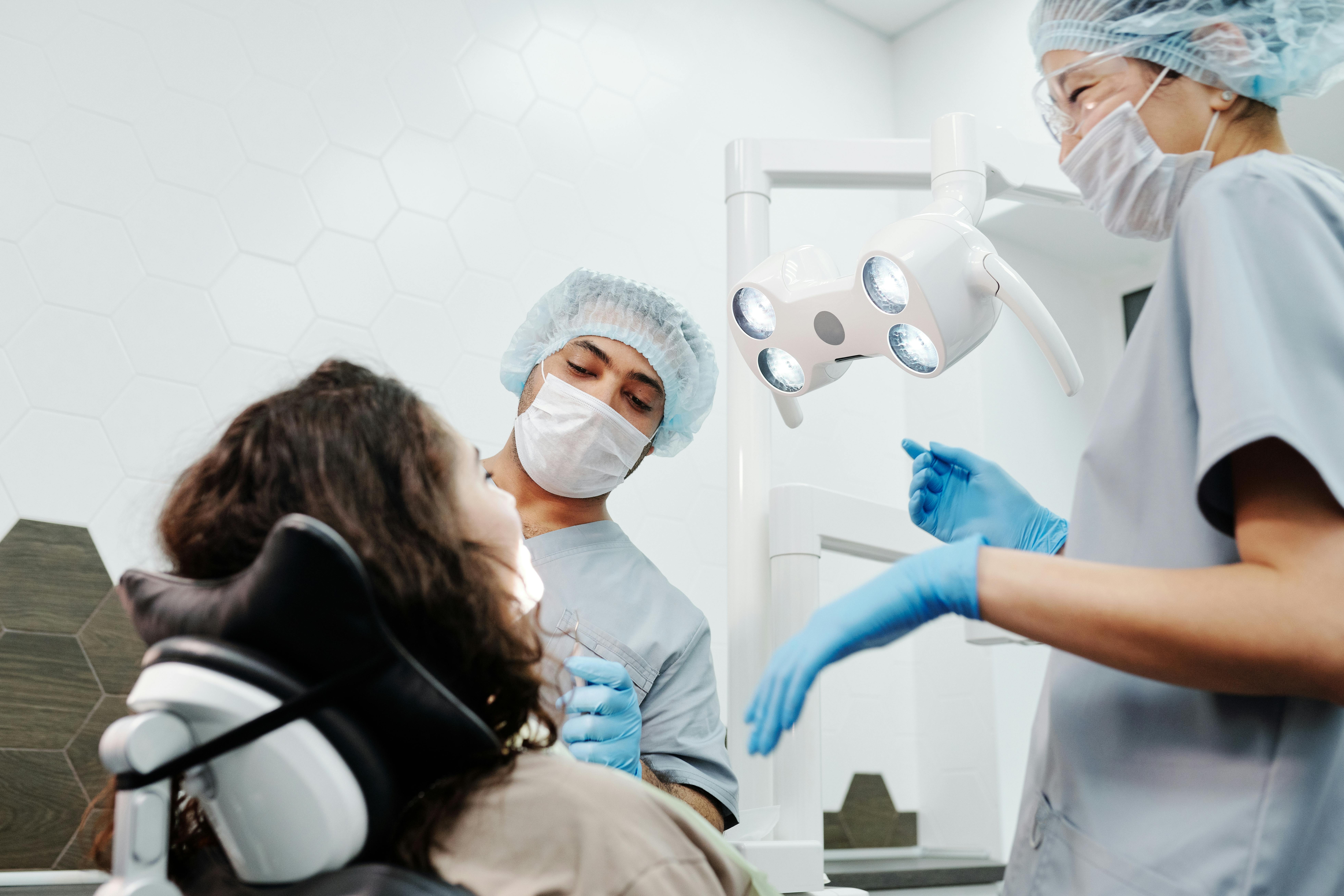 Dentists in a clinic performing a routine checkup on a patient with professional dental equipment.
