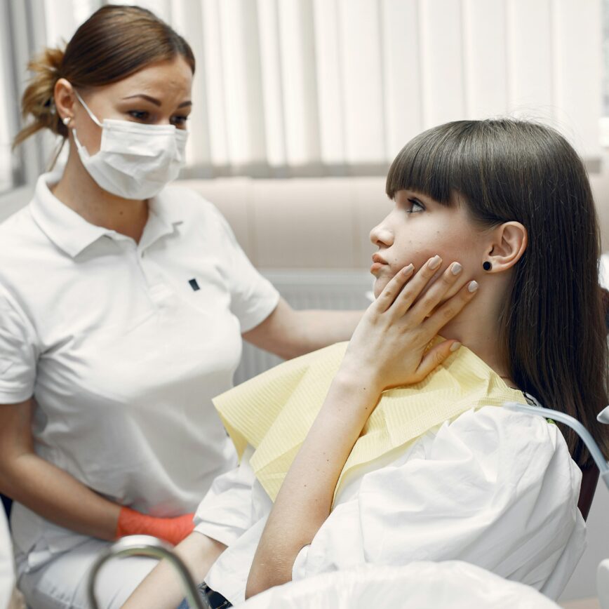 A dentist examining a young woman with toothache in a dental clinic.