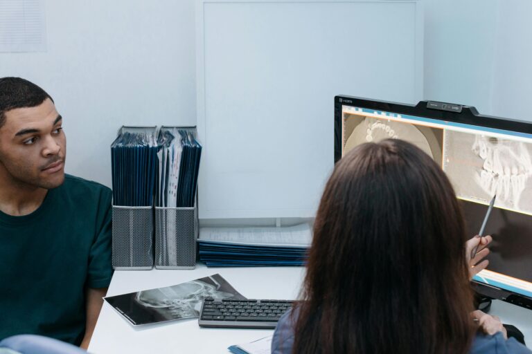 Dentist and patient discussing dental X-ray results in a clinic setting.