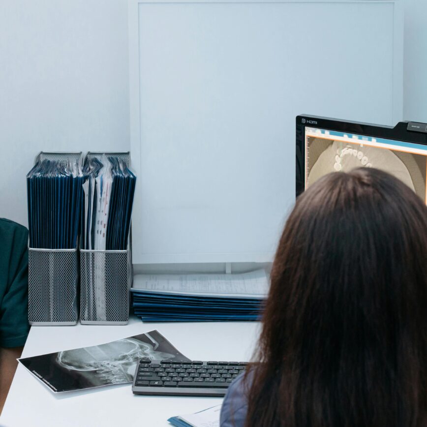 Dentist and patient discussing dental X-ray results in a clinic setting.