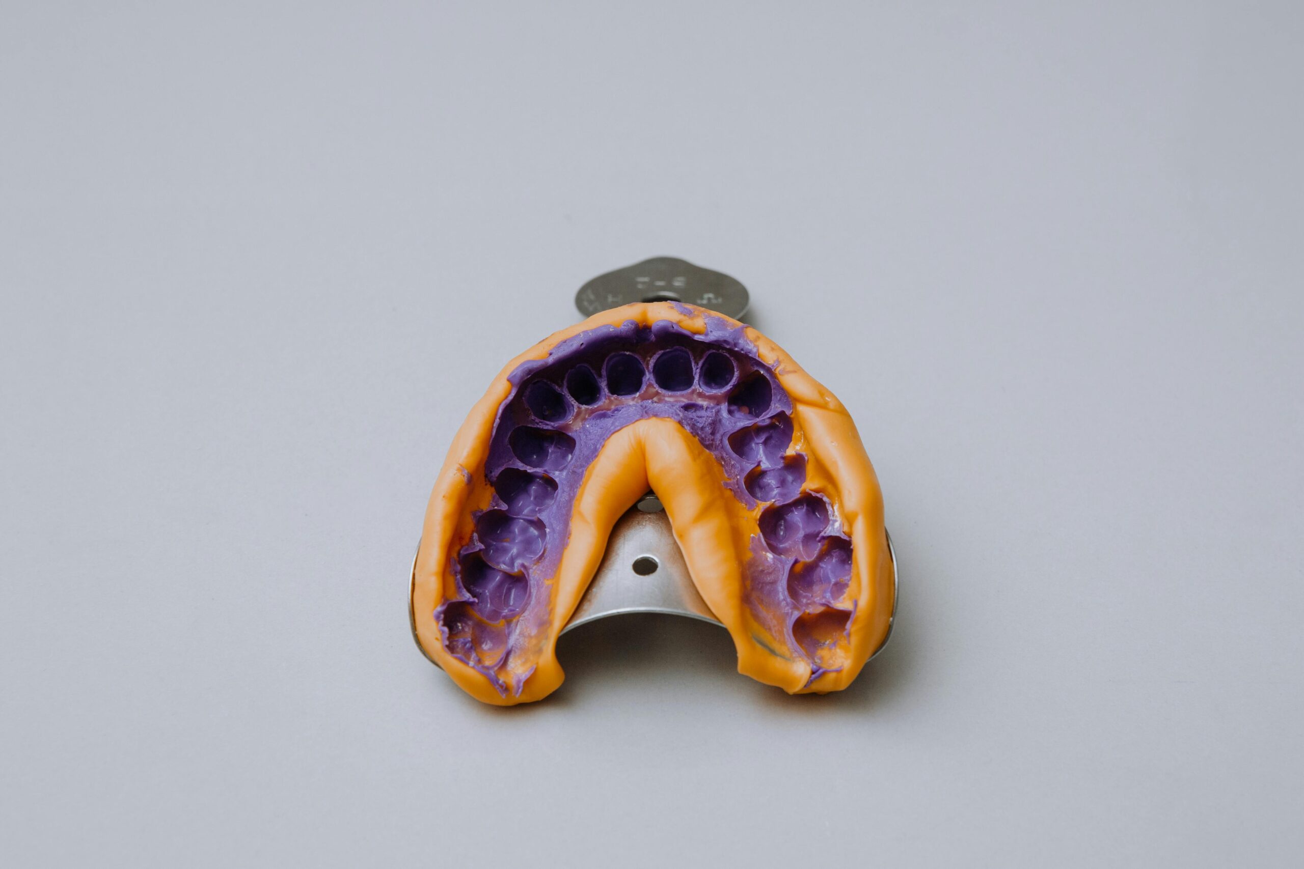 Prothetik Dental impression tray with purple material on a gray backdrop.