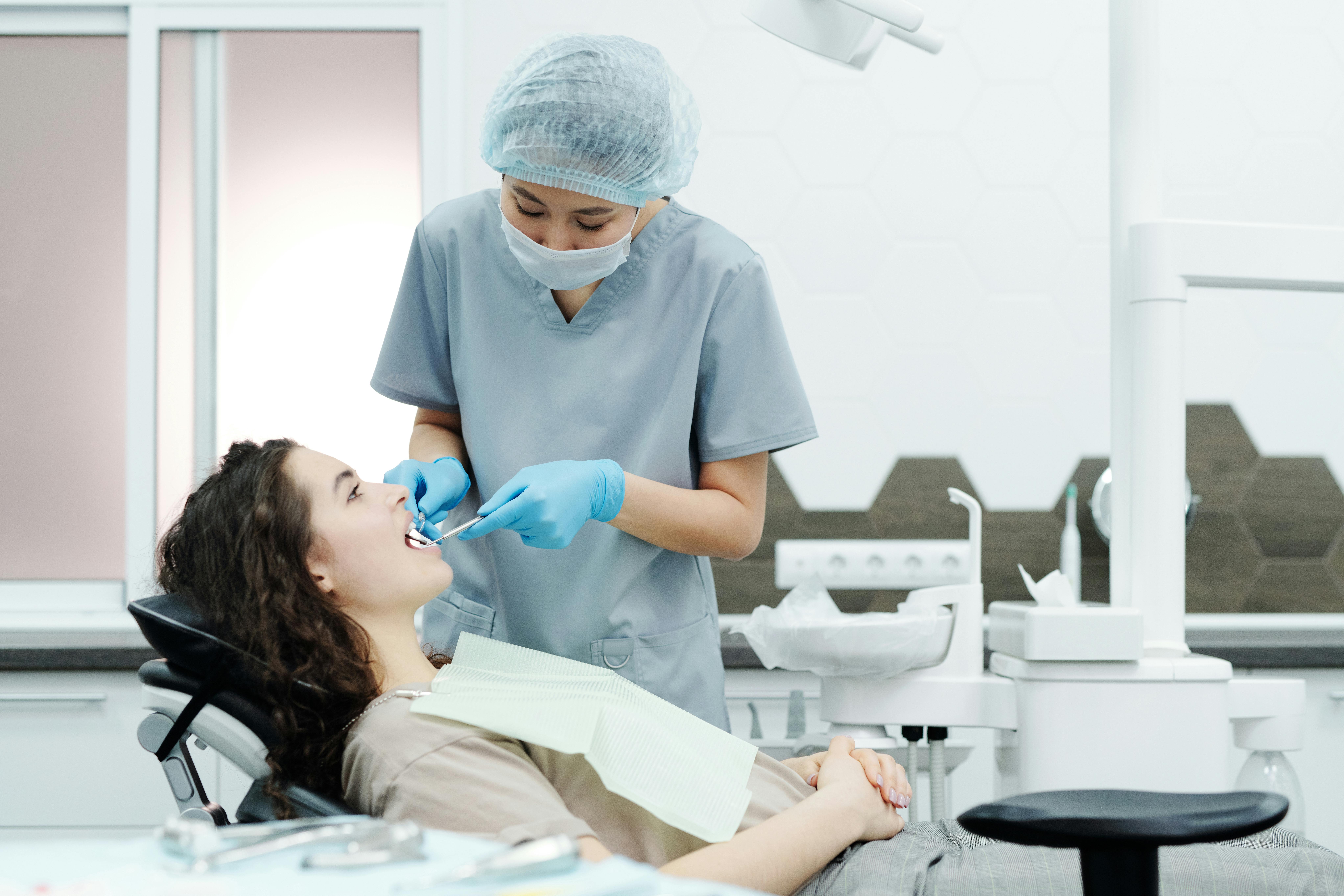 A dentist examines a female patient in a modern dental clinic, ensuring proper dental care.